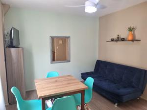 ein Wohnzimmer mit einem blauen Sofa und einem Tisch in der Unterkunft Apartamento 50 metros do Mar da Brava Floripa in Florianópolis