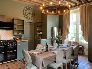 a dining room with a table and chairs and a clock at Le Grand Monnet - Parc - 16 personnes - Rêve au Mans in Coulaines