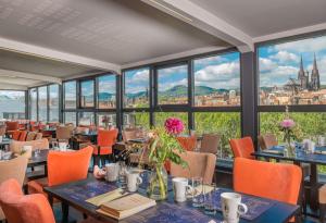 un restaurant avec des tables et des chaises et une vue sur la ville dans l'établissement Hotel Litteraire Alexandre Vialatte, BW Signature Collection, à Clermont-Ferrand