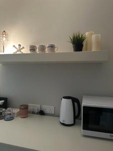- un comptoir de cuisine avec un four micro-ondes et une étagère dans l'établissement أكوا فيلا Aqua Villa, à Madīnat Yanbu‘ aş Şinā‘īyah