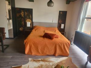 a bedroom with a bed with an orange blanket at Stadslogement Bij de Sassenpoort in Zwolle