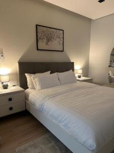 - une chambre avec un lit blanc, 2 tables de nuit et 2 lampes dans l'établissement أكوا فيلا Aqua Villa, à Madīnat Yanbu‘ aş Şinā‘īyah
