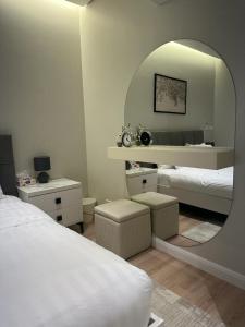Habitación blanca con 2 camas y espejo. en أكوا فيلا Aqua Villa, en Madīnat Yanbu‘ aş Şinā‘īyah