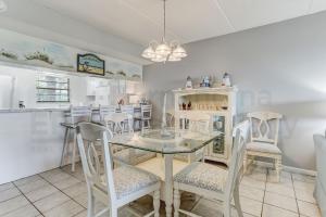 a dining room with a glass table and chairs at Amelia By The Sea 110 in Fernandina Beach