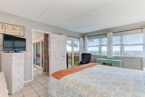 a bedroom with a bed and a tv and windows at Amelia By The Sea 110 in Fernandina Beach