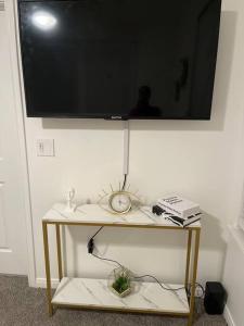 a television on a wall with a table with a clock at Midtown Getaway in Houston