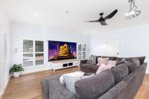 uma sala de estar com um sofá cinzento e uma televisão em Absolute Beachfront Luxury Entertainer - Dundowran Beach em Hervey Bay