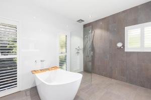 uma casa de banho branca com uma banheira e um chuveiro em Absolute Beachfront Luxury Entertainer - Dundowran Beach em Hervey Bay