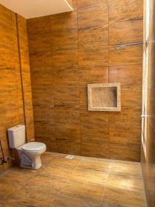 a bathroom with a toilet and a wooden wall at Casa Egípcia em Morro branco - na quadra da praia in Morro Branco