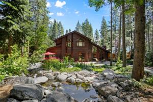 una cabaña de madera en el bosque con un arroyo en Majestic Woods at Tahoe Donner - High End Craftsman w Game Room, Hot Tub, Amenity Access, en Truckee