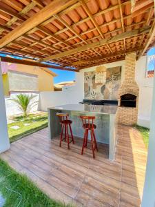 an outdoor kitchen with a bar and stools on a deck at Casa Egípcia em Morro branco - na quadra da praia in Morro Branco