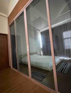 a bedroom with a glass partition with a bed in it at บ้านบางเตยริมน้ำพูลวิลล่า in Ban Bang Rathuk