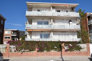 ein weißes Gebäude mit einem Balkon auf einer Ziegelwand in der Unterkunft Apartamento Playa Mar in Castelldefels