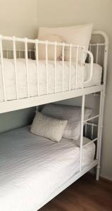 a white bunk bed with white sheets and pillows at Spacious Unit in Convenient Location in Yarrawonga