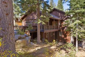 a wooden house with a balcony in the woods at Skislope Manor - Spacious Tahoe Donner 4 BR with Gorgeous Home Theater and Hot Tub in Truckee