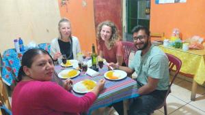 Eine Gruppe von Menschen, die an einem Tisch sitzen und Essen essen. in der Unterkunft El Amauta de los Andes Lodging Erik House in Huaraz