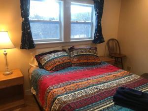 a bedroom with a bed with a red comforter and two windows at The Apartment at Sky Hollow in Rochester