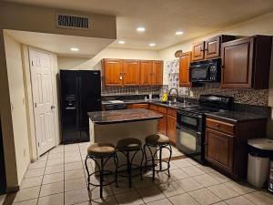 una cocina con armarios de madera y electrodomésticos negros en Chandler Charming Home en Chandler