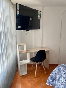 a bedroom with a desk with a tv and a chair at Habitación Privada Cerca al Aeropuerto in Bogotá