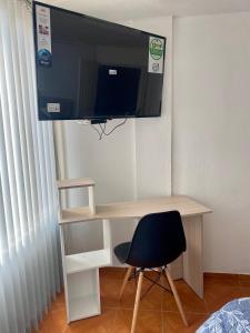 a desk with a chair and a television on a wall at Habitación Privada Cerca al Aeropuerto in Bogotá