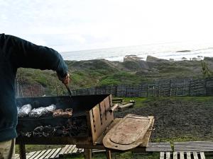 a person is cooking food on a grill at Casa Curanipe in Curanipe
