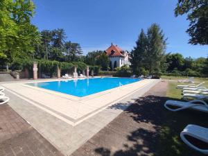 a swimming pool with chairs and a house in the background at Apartments in Balatonudvari 45330 in Balatonudvari