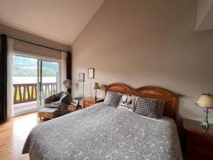 a bedroom with a bed and a chair and a window at Cozy 2 bedrooms condo with stunning Mont Tremblant mountain and lakeview in Mont-Tremblant