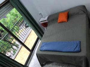 una cama con una almohada naranja junto a una ventana en APARTAMENTO VIAJERO 2 en Buenos Aires