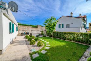 einen Garten mit einem Haus und einem Baum in der Unterkunft Apartments with a parking space Mali Losinj (Losinj) - 16555 in Mali Lošinj