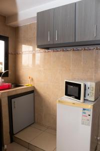 a kitchen with a microwave on top of a refrigerator at Enka Flat Hotel in Abidjan