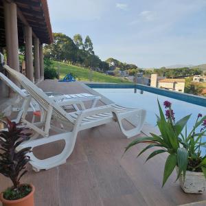 a white lounge chair sitting next to a swimming pool at Casa Ambrósio Capitólio in Capitólio