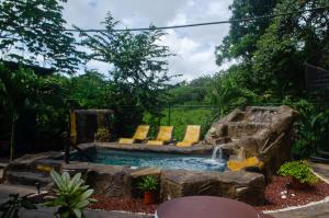 a pool with chairs and a waterfall in a yard at The Jungle Container in Quepos