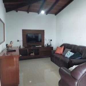 a living room with a leather couch and a tv at Casa Ambrósio Capitólio in Capitólio