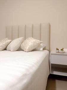 a bed with white sheets and pillows next to a table at Suite Posada Express with Free Airport Shuttle in Santa Cruz de la Sierra
