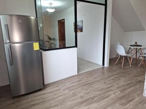 eine Küche mit einem Kühlschrank aus Edelstahl und einem Tisch in der Unterkunft Grande departamento cerca al Shopping y con garage in Santo Domingo de los Colorados