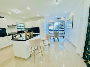 a kitchen and dining room with a counter and chairs at Modern Oasis By The Waves. in Santa Cruz de Barahona