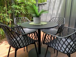 a table and chairs with a potted plant on it at The Place - Culburra Beach in Culburra Beach