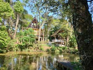 uma casa na floresta ao lado de um rio em Pousada Recanto do Beija Flor em São José dos Pinhais