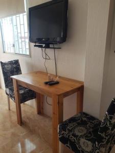 einen Holztisch mit einem TV an der Wand in der Unterkunft Suite privada para 5 personas - #5 Playa Engabao in Playas