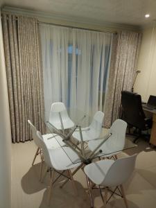 a room with a glass table and white chairs at Purple Olive Guest House in Pretoria