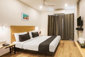 um quarto com uma cama grande e uma televisão em Super Townhouse 176 Rajdhani Residency em Surūrnagar