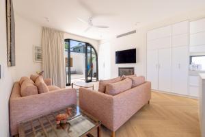 a living room with two couches and a tv at Cooee -Brand new with private pool 350m to beach! in Byron Bay