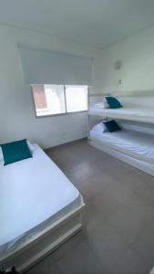 um quarto branco com duas camas em Cabaña Arrecife 07 em Coveñas
