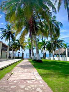een loopbrug met palmbomen voor de oceaan bij Cabaña Arrecife 07 in Coveñas