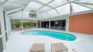 una piscina sotto un tetto in vetro con due sedie di Paradise Naples Pool House a Naples