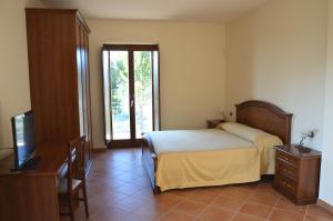 a bedroom with a bed and a desk and a television at Villa Pandora in Agropoli