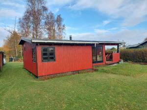 een rood huis met een zwart dak in een tuin bij Holiday home Væggerløse XL in Bøtø By