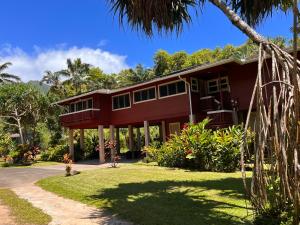 a red house with a palm tree in front of it at River Estate Riverhouse in Hanalei