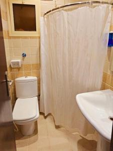 a bathroom with a white shower curtain and a toilet at EWG Mahbas Hotel in Makkah