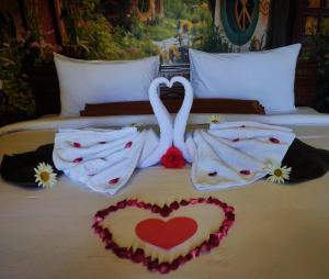 uma cama com dois cisnes feitos para parecer corações em Hotel Nature Bromo and Resort em Pasuruan